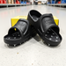 Black cleated sandals with a yellow ProTrac box on a concrete floor.